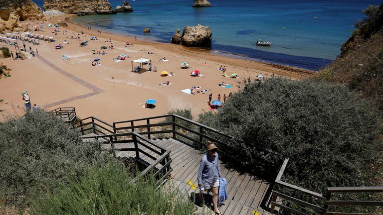 Un hombre sale de la playa de Donna Ana en Lagos, Portugal