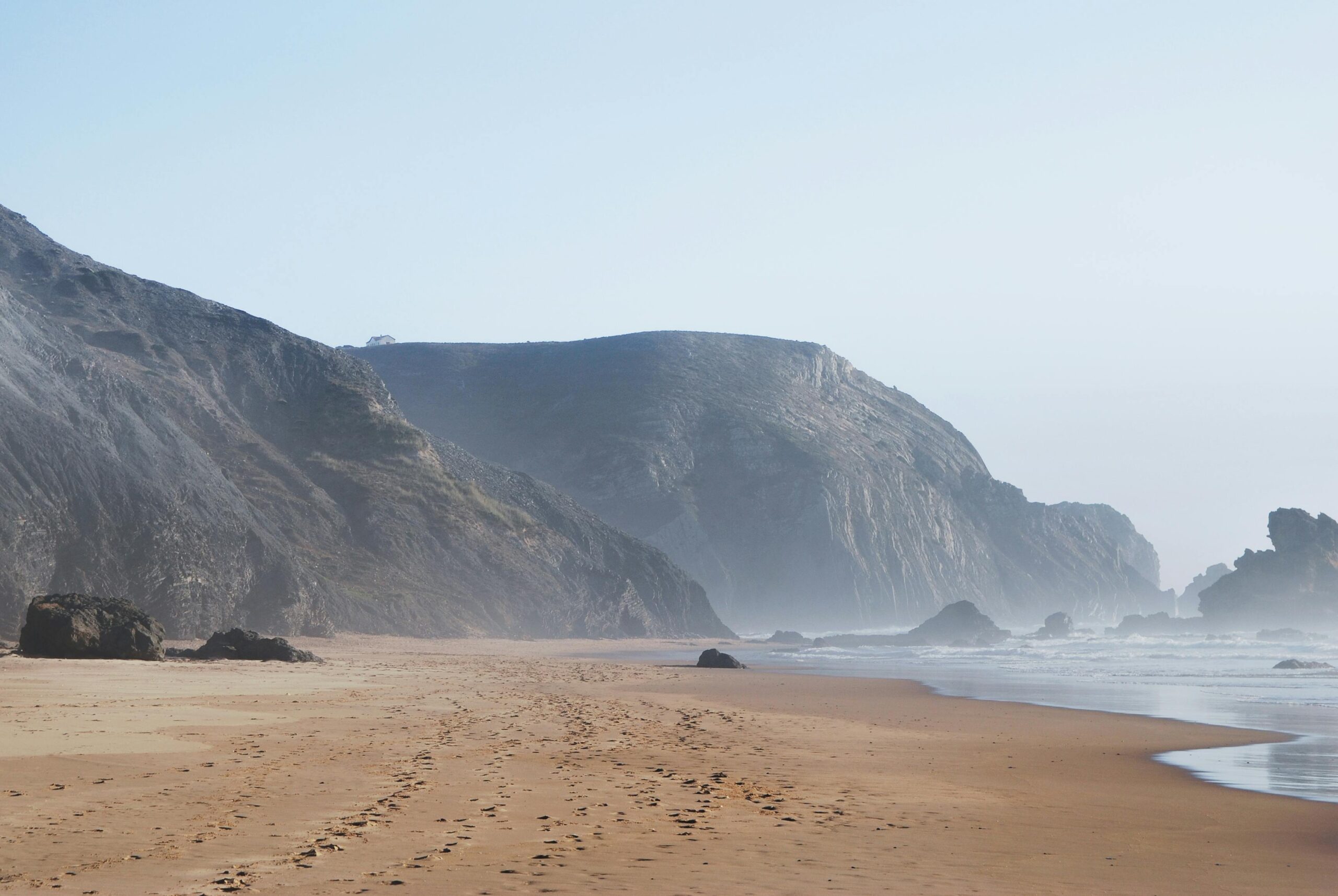 A scenic view of a foggy beach with cliffs in Portugal, capturing the natural beauty of the coast.