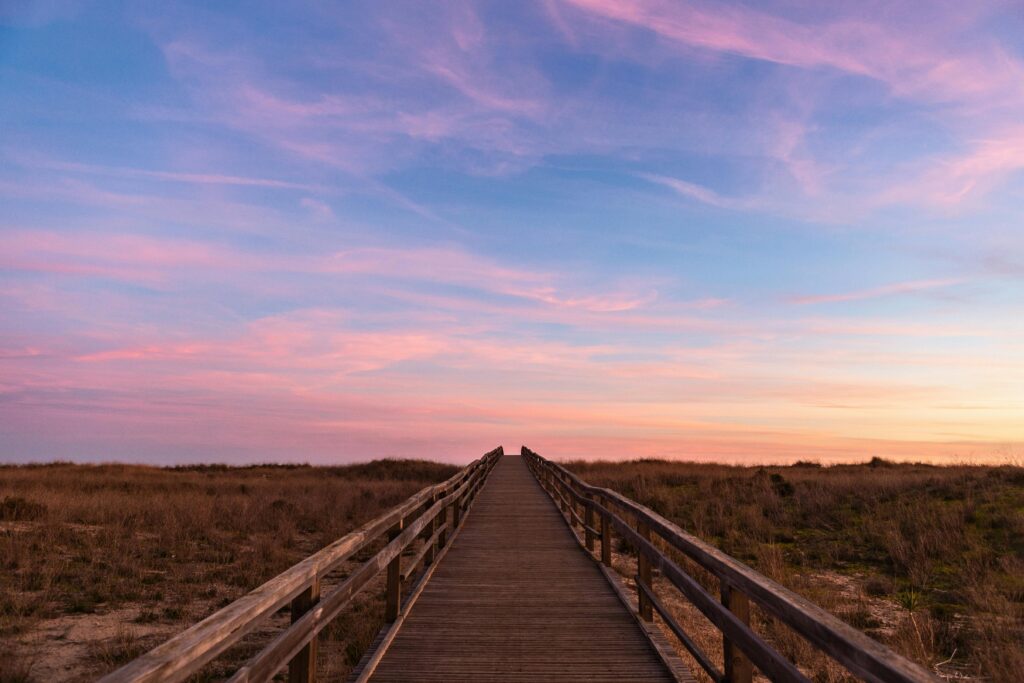 Experience tranquility as the sun sets over a scenic boardwalk in Lagos, Portugal.
