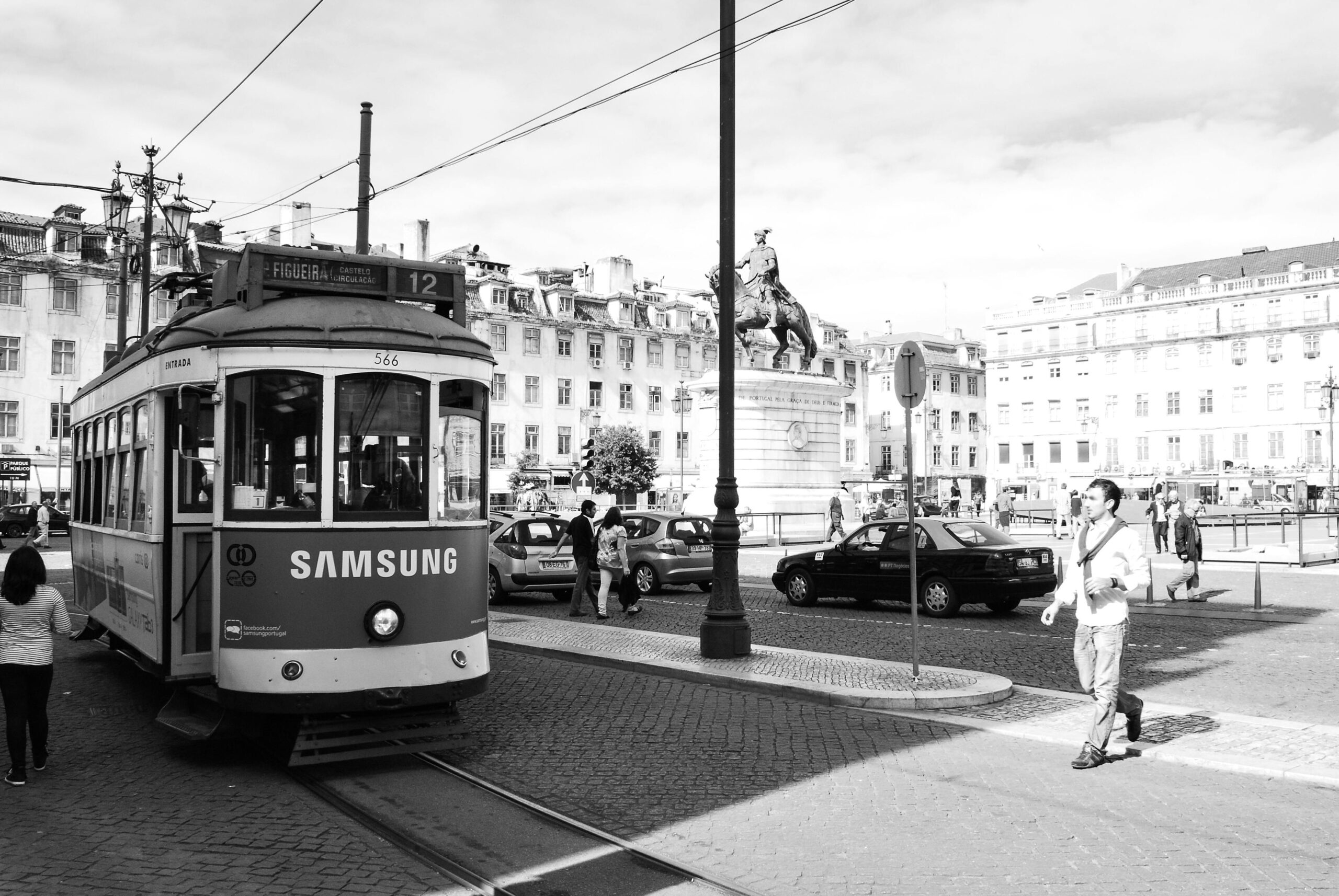 A classic tram traverses Lisbon's bustling city square, epitomizing urban transportation.