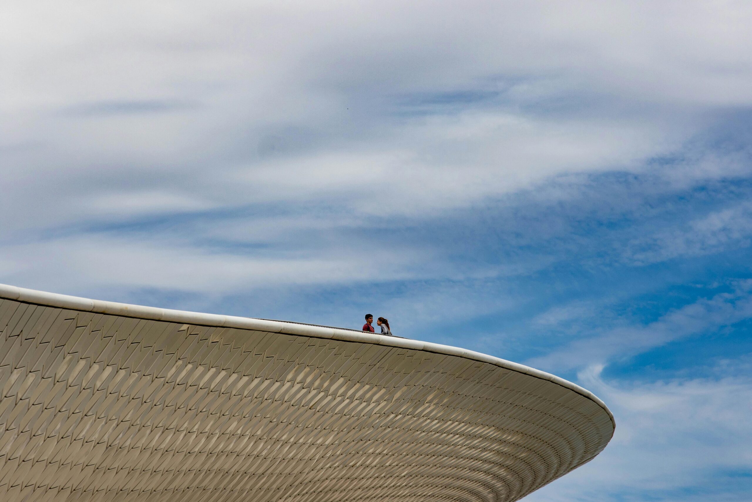 Low angle view of a modern rooftop in Lisbon with two people against a blue sky.