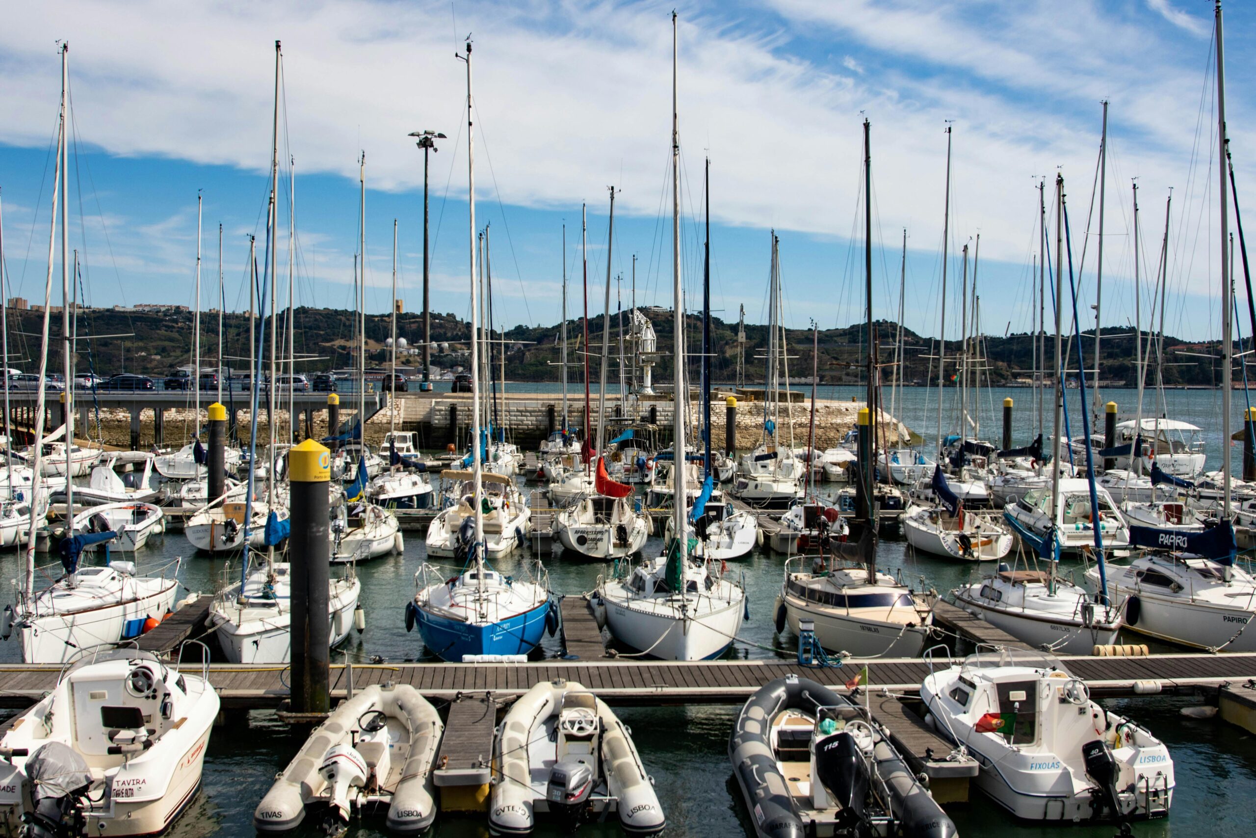 A vibrant marina in Lisbon, Portugal, showcasing docked sailboats and clear skies.