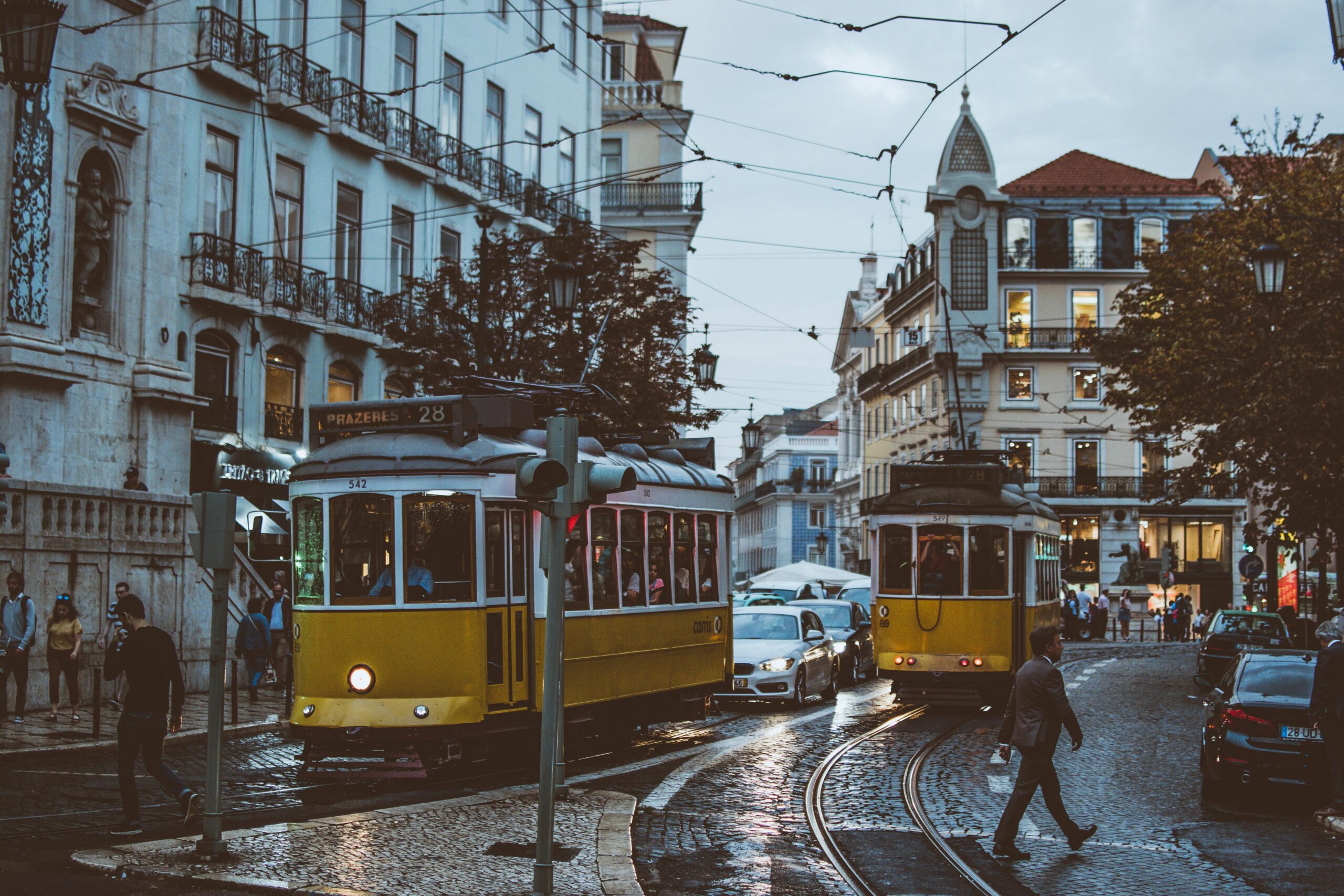 Scenic view of trams navigating the charming streets of Lisbon at dusk, capturing urban life and transportation.