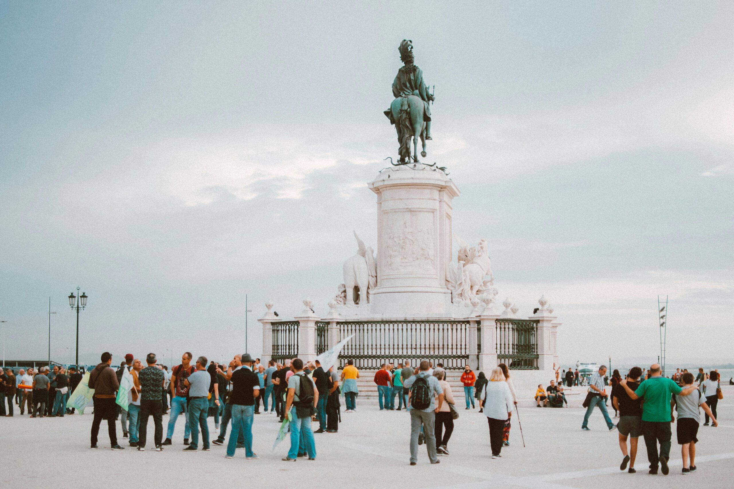 Tourists gather around the iconic statue in Lisbon, Portugal, enjoying a sunny day.