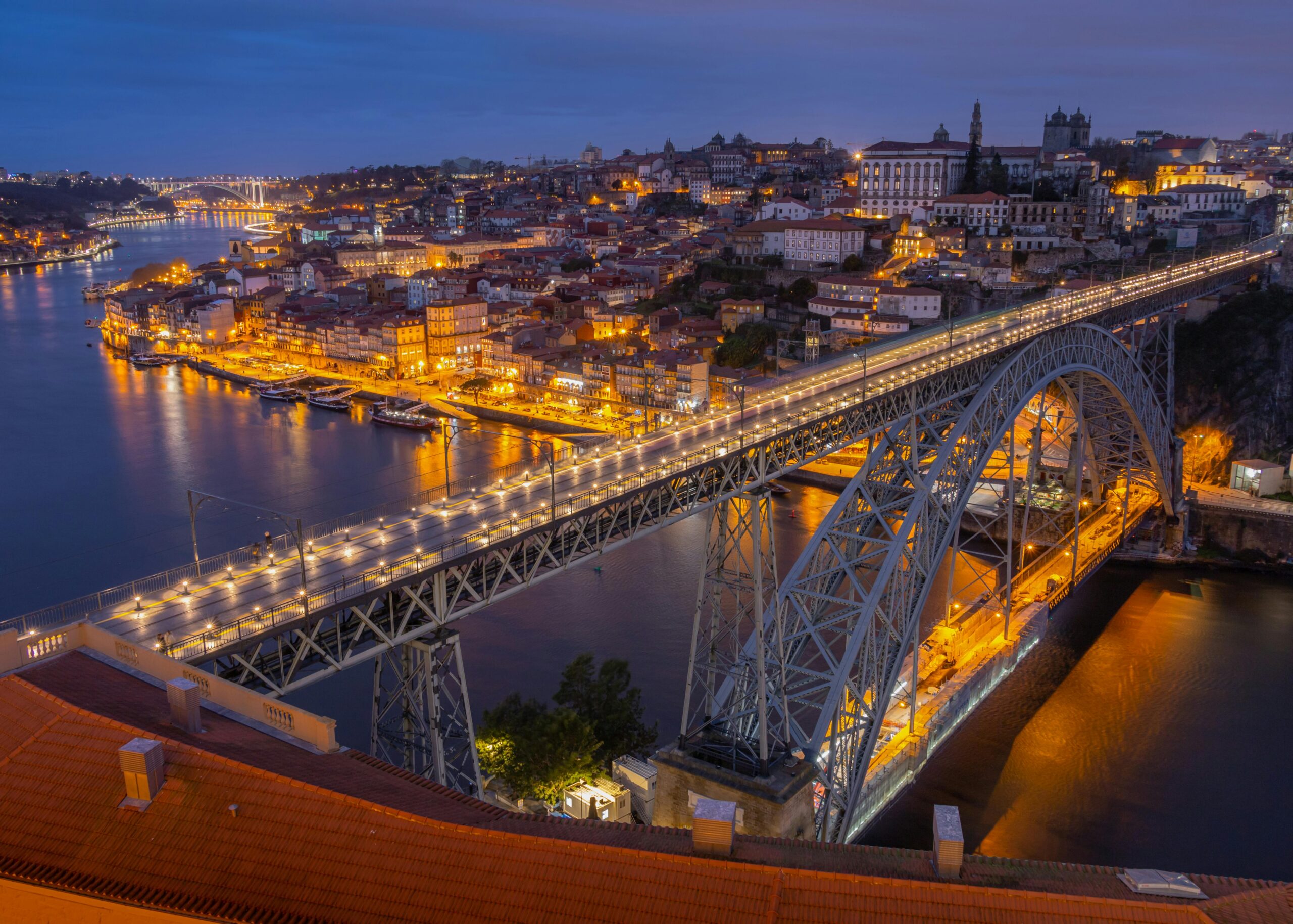 Captivating evening cityscape of Porto featuring the illuminated Luís I Bridge over the Douro River.