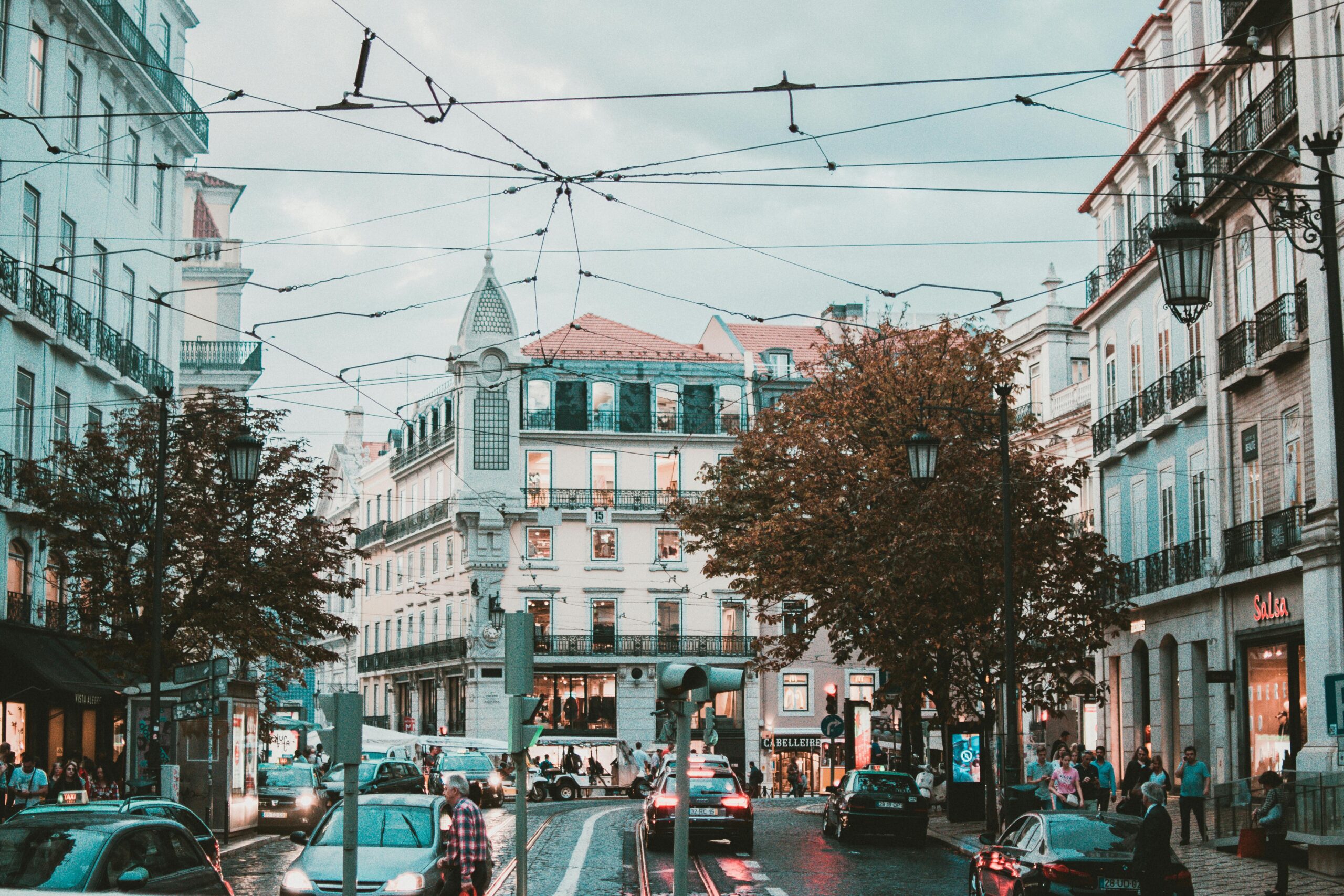 Explore a bustling street scene in Lisbon, Portugal, featuring stunning classic architecture and lively urban traffic.